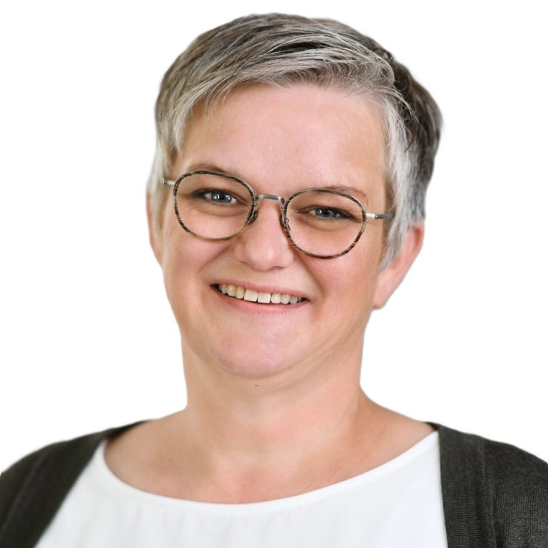 freundlich lächelnde Frau mit grauem Haar und Brille